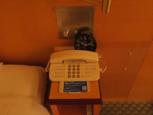 ホテル阪神 シングルルーム 枕元 目覚まし時計と電話が置いてあります