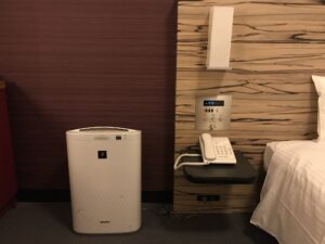ホテル ヴィラフォンテーヌグランド東京田町 スーペリアクイーンルーム 枕元 明かりと目覚まし時計、スイッチ類、電話、加湿空気清浄機があります
