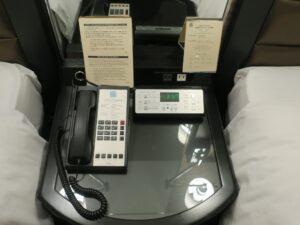JRタワーホテル日航札幌 モデレートツイン 枕元のテーブル 電話と目覚まし時計、スイッチ類、ACコンセントがあります