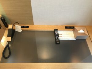 カンデオホテルズ東京新橋 ダブルルーム デスク上 電話とACコンセント、液晶テレビのリモコン、ティッシュがあります