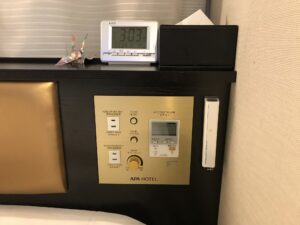 アパホテル 品川 泉岳寺駅前 シングルルーム 枕元 目覚まし時計とACコンセント 非常灯 照明とエアコンのスイッチがあります