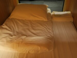 TSUKIMI HOTEL カプセルルーム内 掛け布団と枕、アメニティが手前に置いてあります