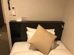 ホテルシュランザCHIBA スーペリアシングル 枕元 電話機、照明とエアコンのスイッチ、ACコンセント、目覚まし時計があります