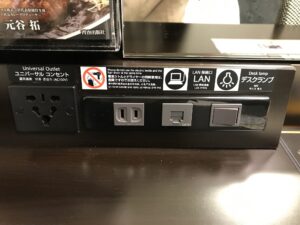 アパホテル 上野駅前 スタンダードルーム デスク回り ユニバーサルコンセント、ACコンセント、LANコネクタ、デスクランプのスイッチがあります