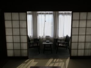 野沢温泉ホテル 和室10畳 バス・トイレなし 障子奥 窓際にテーブルと椅子があります