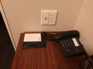 ドーミーイン熊本 セミダブルルーム デスク回り 照明のスイッチ、有線LANポート、メモ、電話があります