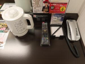 アパホテル 千葉駅前 スタンダードルーム デスク上 電気ポット テレビのリモコン メモ帳 電話機があります