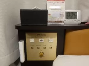 アパホテル 京都駅堀川通 シングルルームB 枕元のスイッチ 照明のスイッチとACコンセント、USBポート、ティッシュ、目覚まし時計、非常灯があります