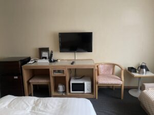 ホテルハーバー横須賀 シングルルーム デスク、冷蔵庫、液晶テレビ、電子レンジ、椅子、サイドテーブルがあります