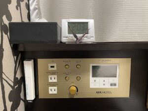 アパホテル＆リゾート 西新宿五丁目タワー シングルルーム 枕元 ティッシュと目覚まし時計、非常灯、USBポート、ACコンセント、明かりとエアコンのスイッチがあります