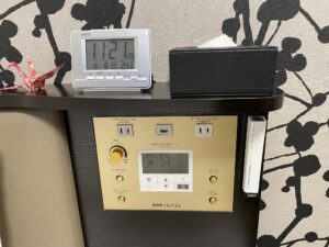 アパホテル 東新宿歌舞伎町タワー スタンダードルーム 枕元 目覚まし時計、ティッシュ、ACコンセント、USBポート、照明とエアコンのスイッチ、非常灯があります
